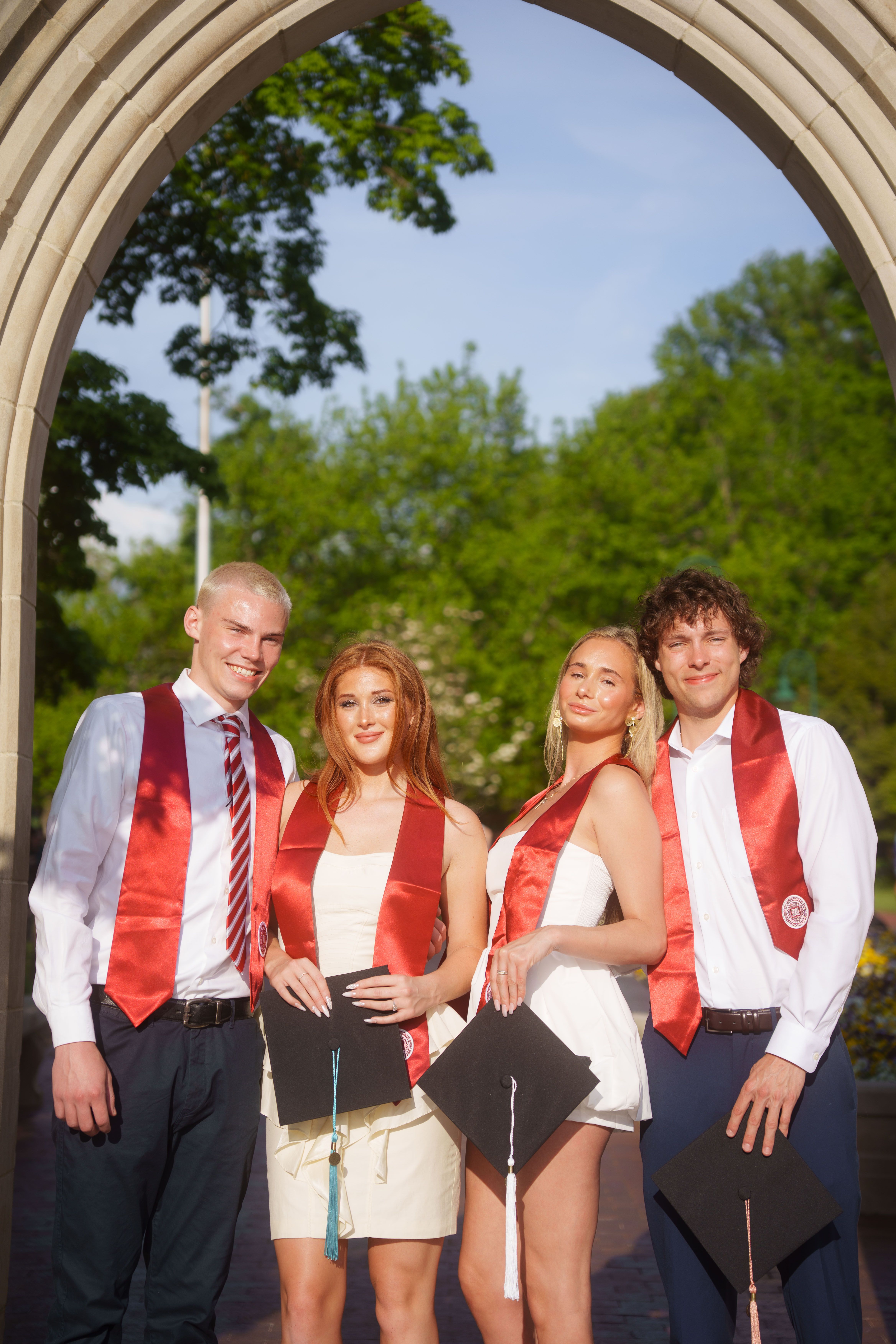 Three graduates in white dresses at sunset.