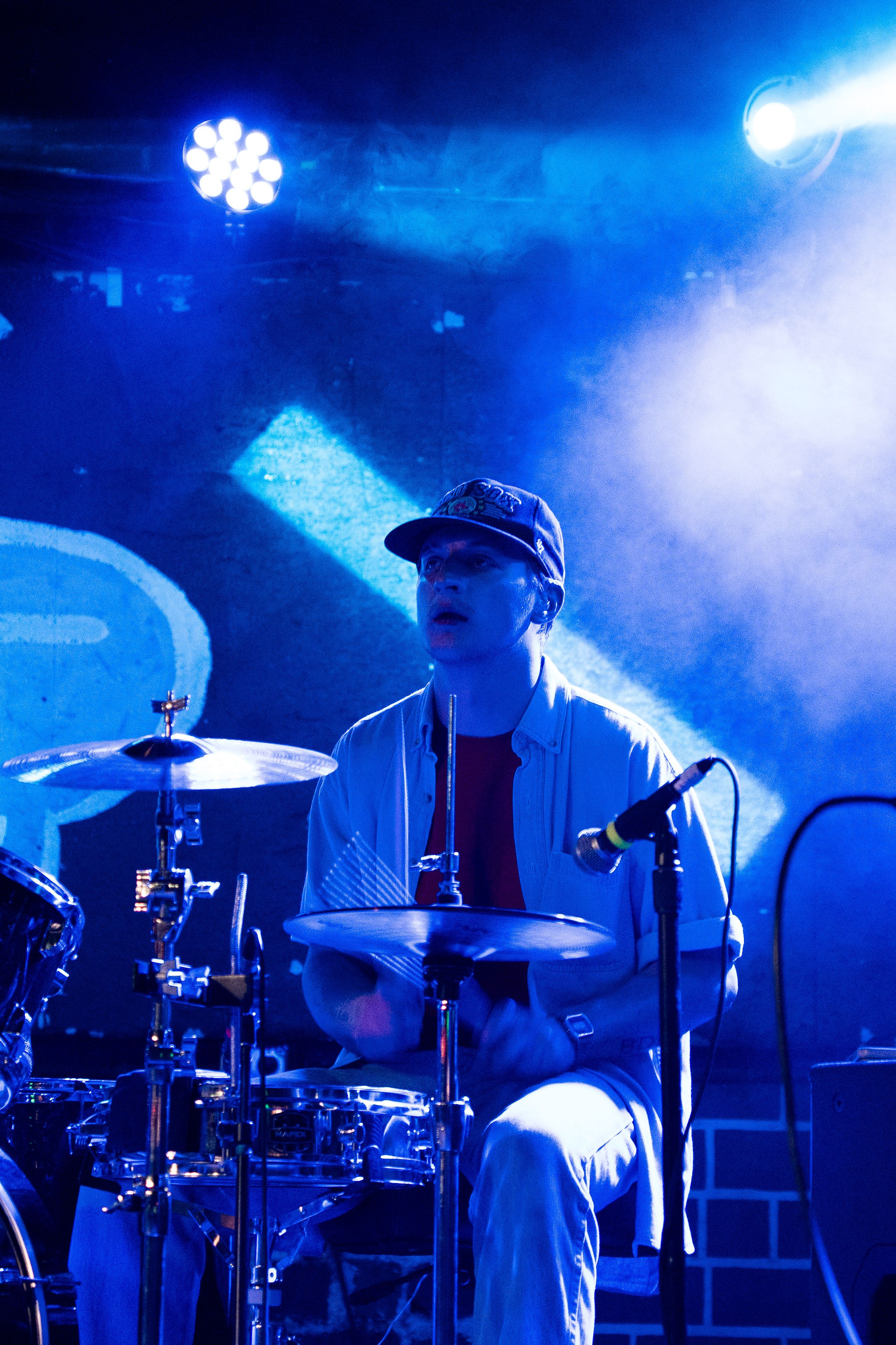 Drummer looking up, lit up in blue.