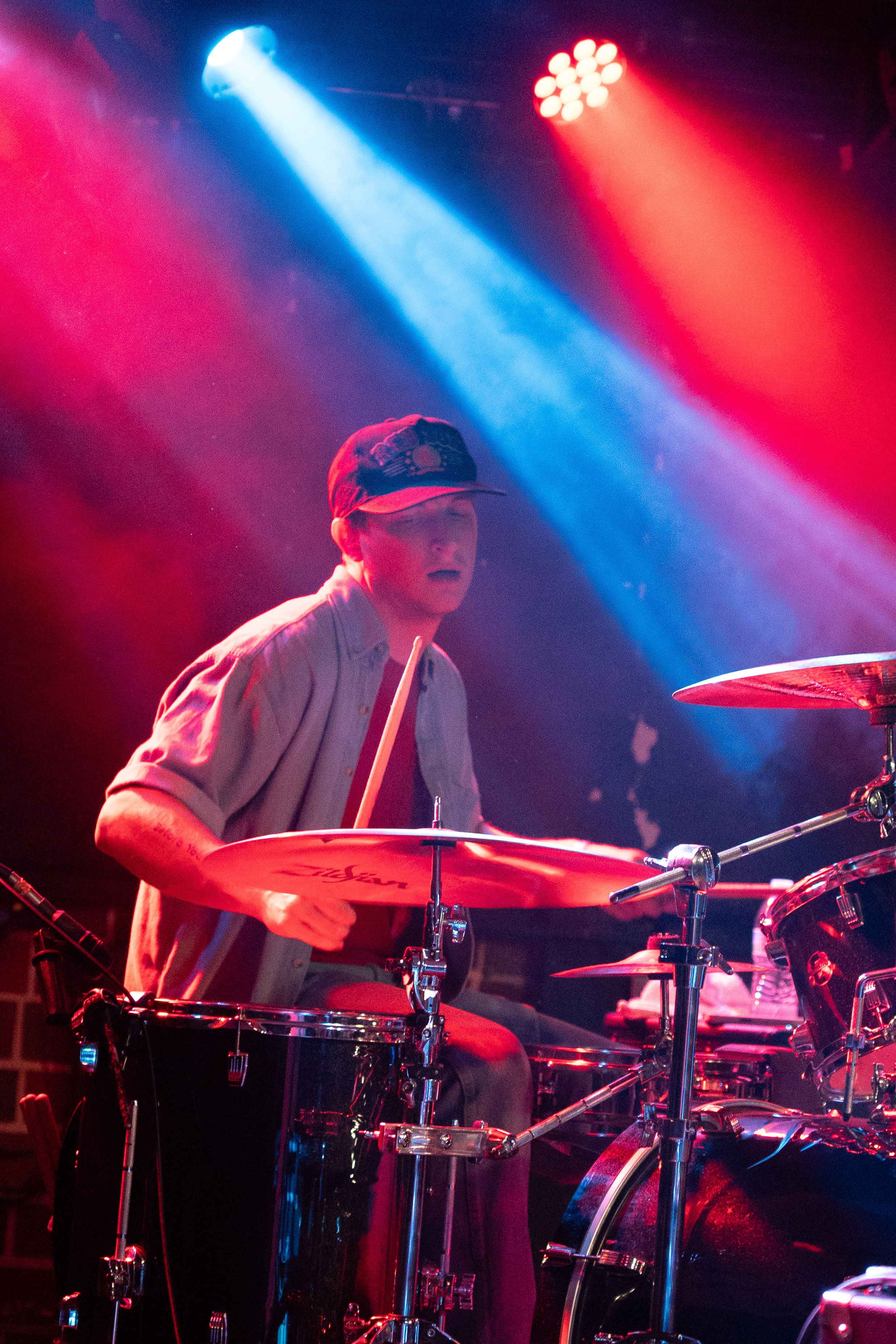 Drummer looking down with cymbals in the foreground.
